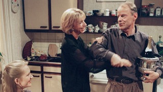 Das passiert selten genug: Berta (Ute Mora, Mitte) und Hajo (Knut Hinz) lassen die Korken knallen; Lisa (Sontje Peplow) freut sich mit den beiden.
