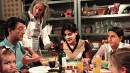 Die Wohnung ist zum Bersten voll: Marcella (Sara Turchetto, 4.v.l.) und Giovanna (Serena Fiorello, 2.v.r.) sitzen neben Paula, Paolo (Sigo Lorfeo), Wanda (Maria Wachowiak-Holonbeck, 3.v.l.) und Irina bald auch noch mit am Tisch.