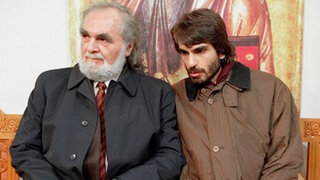 Disput vor der Taufe: Panaiotis (Kostas Papanastasiou, links) und Vasily (Hermes Hodolides) können sich nicht über den Vornamen des Täuflings einigen.