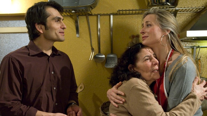 Elena (Domna Adamopoulou, Mitte) und Sandra (Jennifer Steffens) fallen sich tränenreich in die Arme. Auch Vasily (Hermes Hodolides) ist froh, das Elena so verständnisvoll ist.
