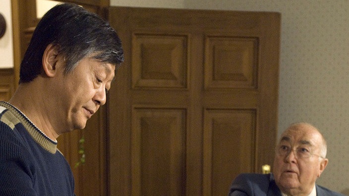 Dr. Dressler (Ludwig Haas, rechts) mistet seine Wohnung aus – schließlich braucht er Platz für Hannelore. Gung (Amorn Surangkanjanajai) hilft beim Aufräumen.