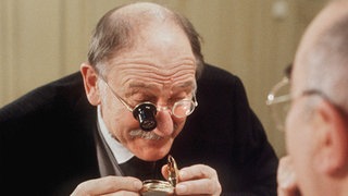Dr. Dressler (Ludwig Haas) übergibt Hubert Koch (Robert Zimmerling, links) eine alte Uhr zur Reparatur.