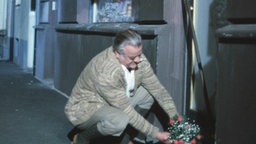 Egon legt Blumen vor Isoldes Friseursalon