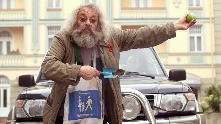 Ein ausgeschlafener Penner: Harry (Harry Rowohlt) stoppt den Verkehr auf der Lindenstraße, um den Fußgängern vor dem Supermarkt ein gefahrloses Überqueren der Fahrbahn zu ermöglichen.