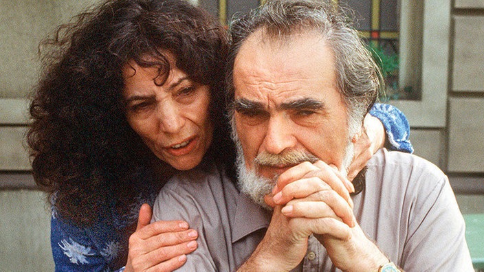 Elena (Domna Adamopoulou) tröstet ihren verzweifelten Ehemann (Kostas Papanastasiou), dem sie die Affäre mit Tanja verziehen hat.