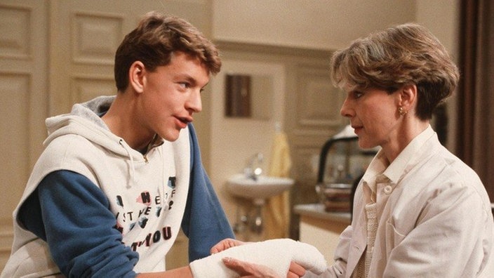 Elisabeth (Dagmar Hessenland) verbindet an Dresslers Stelle Bennys (Christian Kahrmann) Arm.