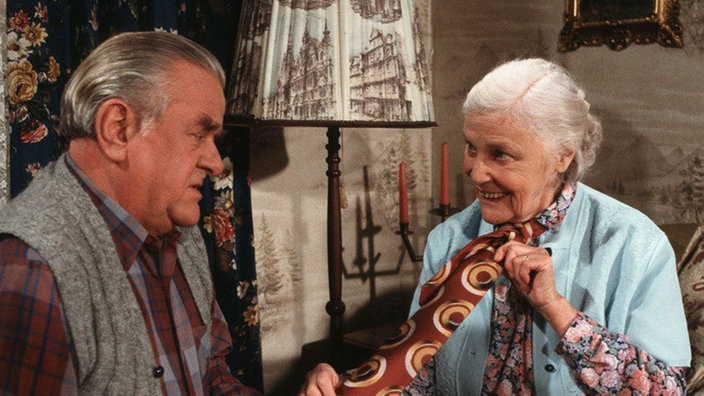 Else (Annemarie Wendl) demonstriert ihrem Egon (Wolfgang Grönebaum) was sie sich ausgedacht hat, damit sie die Reise ins Schönheitsparadies antreten kann.