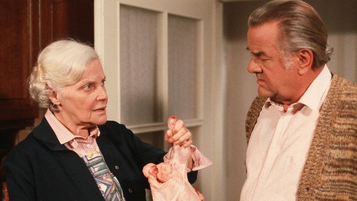 Else (Annemarie Wendl) hat von Helga ein Hähnchen geschenkt bekommen. Egon (Wolfgang Grönebaum) ist skeptisch.