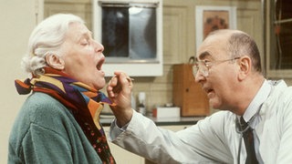 Else (Annemarie Wendl) ist stark erkältet. Dr. Dressler (Ludwig Haas) erteilt ihr nach seiner Untersuchung praktisch Redeverbot.