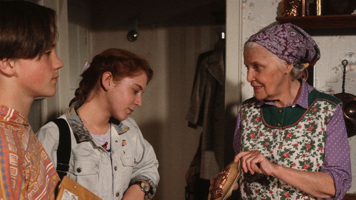 Else (Annemarie Wendl, rechts) überreicht Klaus (Moritz A. Sachs) Post für Helga und Iffi (Rebecca Siemoneit-Barum) Dürers "Betende Hände".