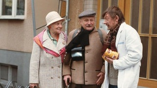 Else Kling (Annemarie Wendl) und Franz Wittich (Martin Rickelt, rechts) gehen auf große Reise. Franz Schildknecht (Raimund Gensel) verabschiedet die beiden.