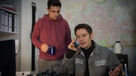 Enzo schaut sauer den telefonierenden Timo an