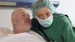 Erich (Bill Mockridge) schlägt Helga (Marie-Luise Marjan) vor, Professor Melchior aus Dank für die geleistete Arbeit einzuladen.
