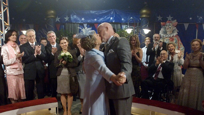 Erst das Ja-Wort, dann der Kuss: Helga (Marie-Luise Marjan) und Erich (Bill Mockridge) heiraten zum zweiten Mal – diesmal im Zirkus. Freunde und Nachbarn haben als Überraschung das Zirkuszelt samt Programm gemietet.