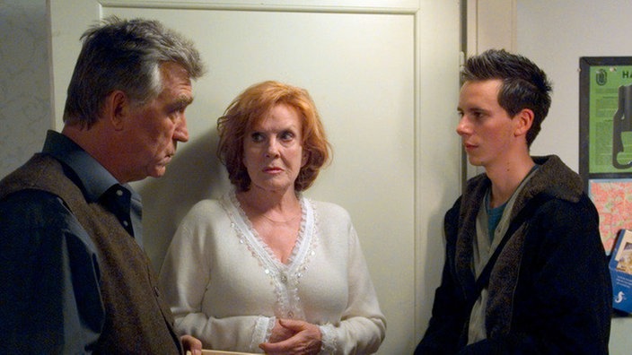 Fabian (Roman Haubner, rechts) bringt Bruno (Heinz Marecek) eine teure Flasche Wein als Geschenk vorbei. Isolde (Marianne Rogée) ist davon alles andere als angetan.