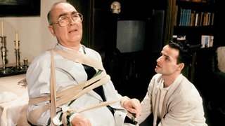 Frank (Christoph Wortberg, rechts) fesselt seinen Vater (Ludwig Haas), damit dieser ihn nicht von seinem Vorsatz, Robert zu erschießen, abhalten kann.
