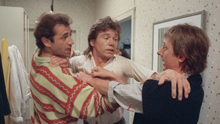 Franz Schildknechts (Raimund Gensel, rechts) Geduld ist am Ende: Wütend stürzt er sich auf Nossek (Dietrich Siegl, links), den vermeindlichen Verführer seiner Tochter. Benno Zimmermann (Bernd Tauber) greift ein.