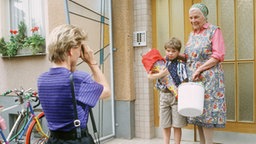 Gabi macht ein Foto von Max mit Schultüte und Else