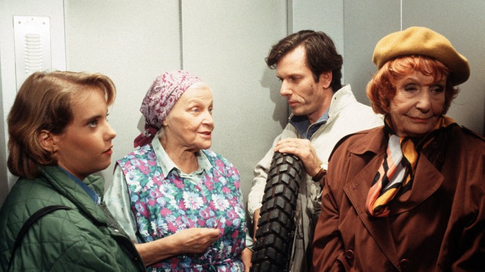 Genervt lauschen Amélie (Anna Teluren, rechts), Valerie (Nadine Spruß, links) und Kurt (Michael Marwitz) Elses (Annemarie Wendl) Ausführungen, als sie plötzlich Hilferufe aus der Wittich-Wohnung hören.