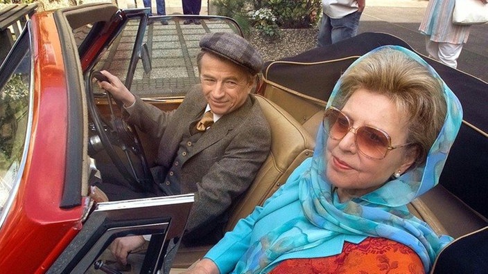 Großer Auftritt: Helga (Marie-Luise Marjan) wird von Herrn Moser (Gerd Lohmeyer) in einem eleganten Cabrio abgeholt und zu einem festlichen Diner kutschiert.