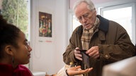Hans zahlt an der Supermarktkasse