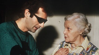 Hausmeisterin Else Kling (Annemarie Wendl) hat eine wichtige Nachricht für Stefan Nossek (Dietrich Siegl).