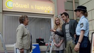 Helga, Josi, Alex und Maria stehen vor dem Schaufenster von "Träwel und Iwends"
