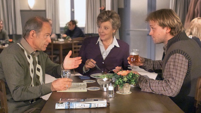 Helga (Marie-Luise Marjan) erfährt von Hajo (Knut Hinz, links), wie sehr sich Erich für sie eingesetzt hat. Klaus (Moritz A. Sachs) hört aufmerksam zu.