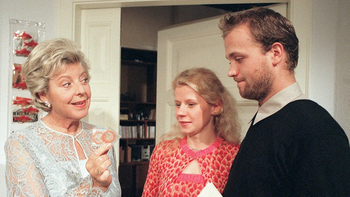 Helga (Marie-Luise Marjan, links) schenkt Nina (Jacqueline Svilarov) und Klaus (Moritz A. Sachs) nicht nur eine Reise, sondern überreicht zugleich unverzichtbare Accessoires.
