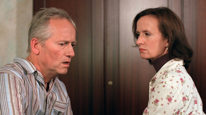 Hört, hört: Hans (Joachim Hermann Luger) erhält einen alarmierenden Anruf von seinem Arbeitgeber. Anna (Irene Fischer) macht sich Sorgen um ihren Mann.