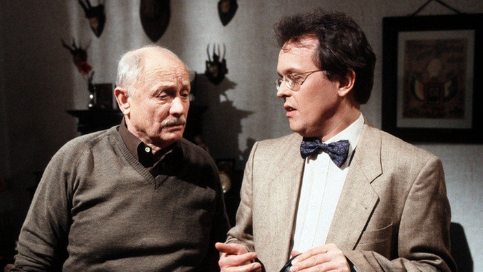 Hülsch (Horst D. Scheel, rechts) erklärt Onkel Franz (Martin Rickelt) - der gerade seine Wohnung desinfiziert - das alle Mieter außer Else mit David als Untermieter einverstanden sind.