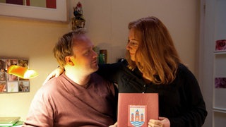 Iffi und Klaus halten ihre Hochzeitsurkunde in den Händen