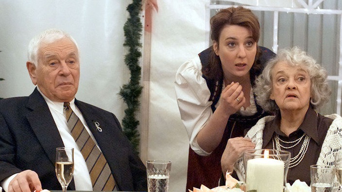 Ines (Birgitta Weizenegger, Mitte) verplappert sich bei Hilde (Giselle Vesco) und Oskar (Reinhold Lampe) und verrät, dass Bruno der Ex-Mann von Rosi ist.