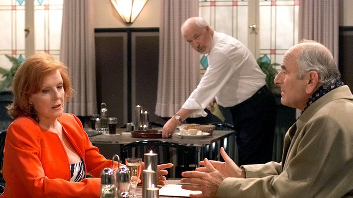 Isolde (Marianne Rogée) stellt Herrn Hey (Fred Berhoff, rechts) wegen der feuchten Grundmauern zur Rede. Hausmeister Erich (Bill Mockridge) hört aufmerksam zu.