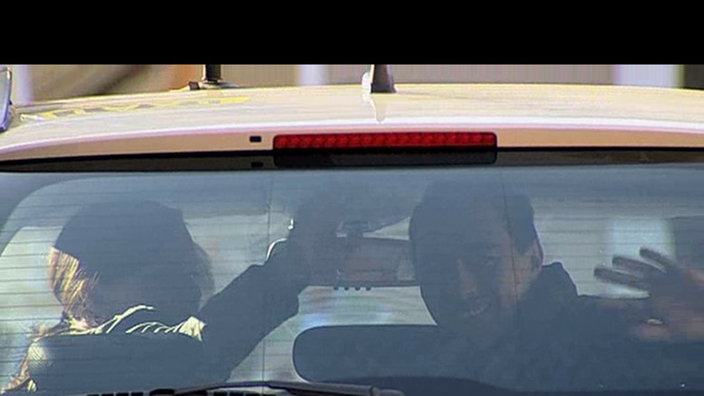 Kitty und Tom sitzen im Taxi und winken zum Abschied