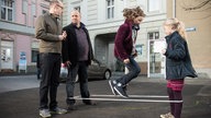Klaus, Mila und Antonia spielen Gummitwist, Philipp steht daneben