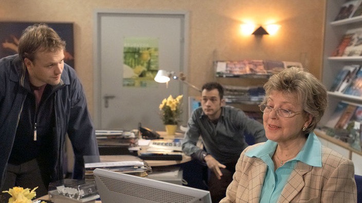 Klaus (Moritz A. Sachs, links; Mitte: Joris Gratwohl) kündigt Helga (Marie-Luise Marjan) ein Fernsehteam an. Die hält das Ganze für einen Aprilscherz.