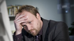 Klaus sitzt verzweifelt am Schreibtisch