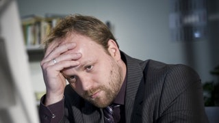 Klaus sitzt verzweifelt am Schreibtisch