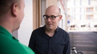 Klaus und Philipp treffen sich freudig vorm Naro-Supermarkt
