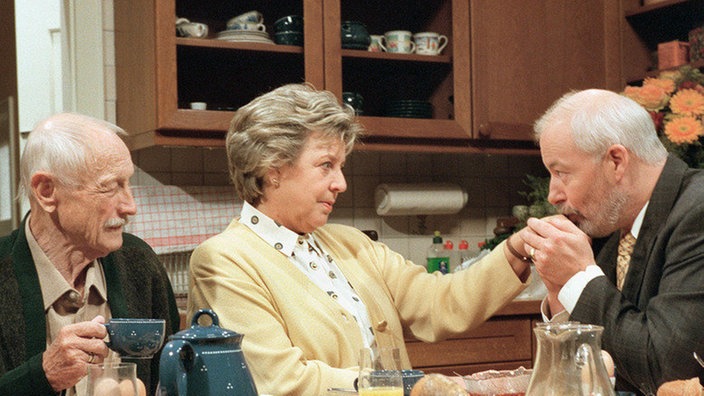 Küss' die Hand, gnä' Frau: Erich (Bill Mockridge, rechts) macht Helga (Marie-Luise Marjan) heftige Avancen - und wird dabei aufmerksam von Onkel Franz (Martin Rickelt) beäugt.