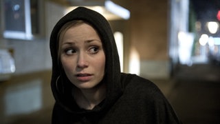 Lea läuft im schwarzen Kapuzenpulli durch die Nacht