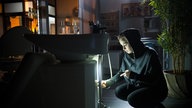 Lea manipuliert im dunklen Friseursalon eine Waschmaschine