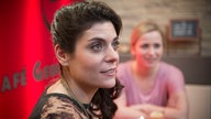 Marcella sitzt mit Lea an einem Tisch im Café George