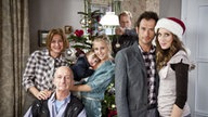 Maria, Adi, Lukas, Caro, Ernesto, Alex und Josi posieren für ein Familienfoto zu Weihnachten