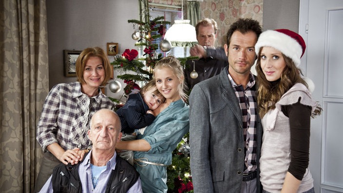 Maria, Adi, Lukas, Caro, Ernesto, Alex und Josi posieren für ein Familienfoto zu Weihnachten