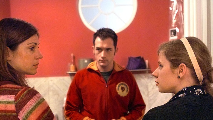 Marion (Ulrike C. Tscharre, links) und Nina (Jacqueline Svilarov) erklären dem wütenden Alex (Joris Gratwohl), warum sie ihn in der Wohnung eingesperrt hatten.