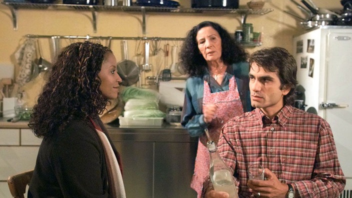 Mary (Liz Baffoe, links) will mit Nikos für längere Zeit nach Nigeria reisen. Elena (Domna Adamopoulou) und Vasily (Hermes Hodolides) sind darüber alles andere als begeistert.