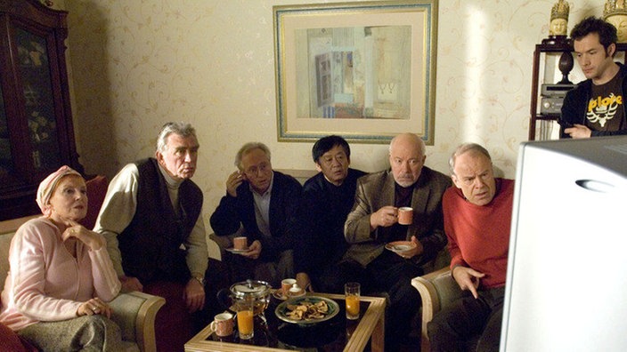 Mit einem Tanz-Video soll die künftige „Boygroup“ auf ihren Auftritt vorbereitet werden (v.l.: Marianne Rogée, Heinz Marecek, Joachim Hermann Luger, Amorn Surangkanjanajai, Bill Mockridge, Knut Hinz, Joris Gratwohl).