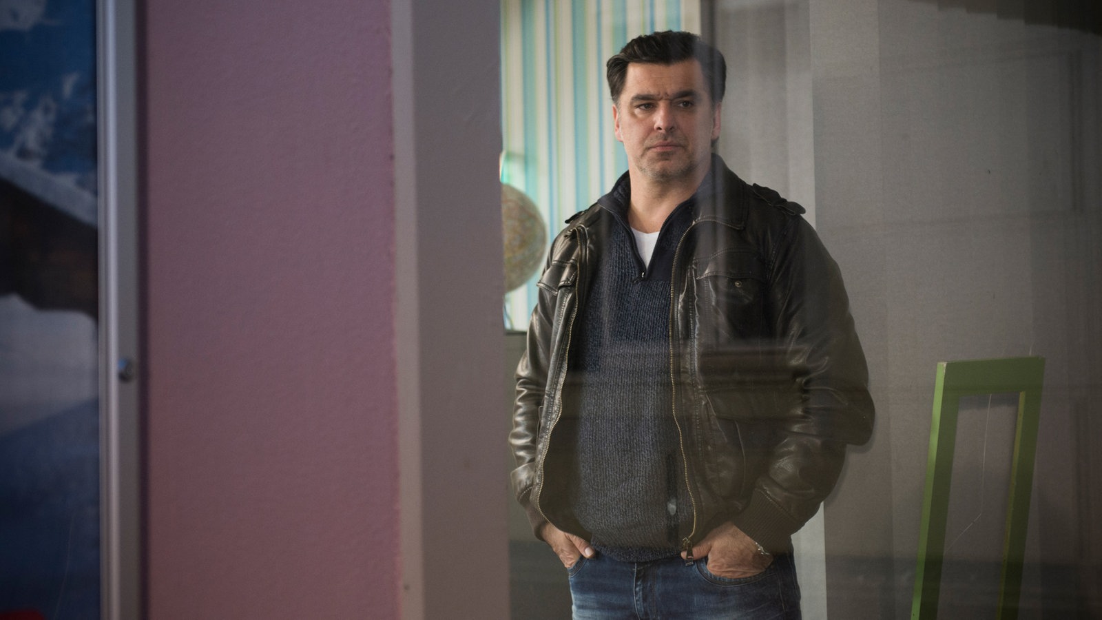 Murat guckt aus dem Reisebüro heraus